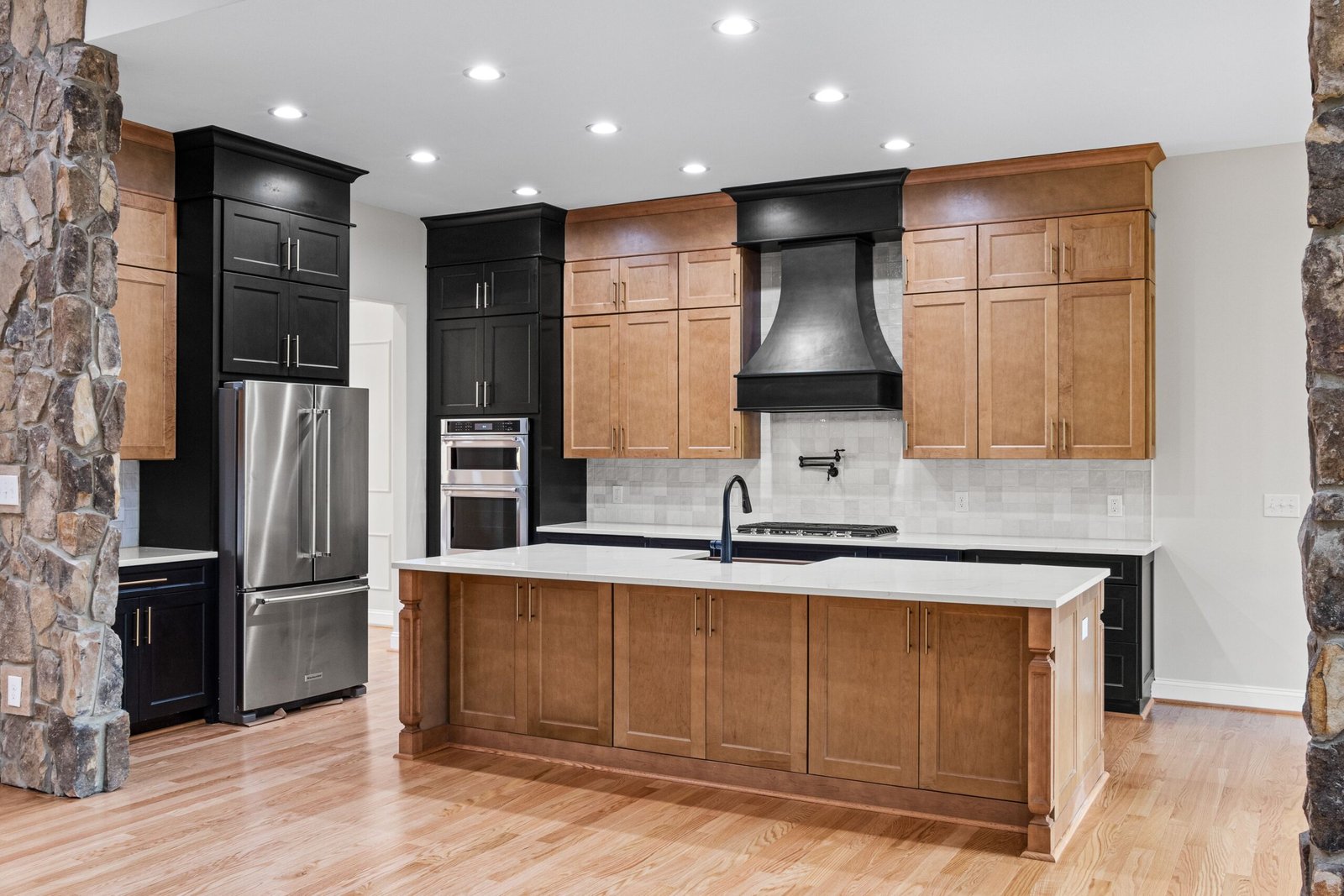 Spacious modern kitchen with wooden cabinetry and stone accents, featuring high-end appliances.